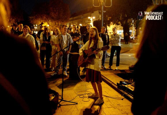 YOUNG PEOPLE CONGREGATE IN THE STREETS BEFORE CURFEW, SINGING AND DANCING TO RELEASE TENSION AND COLLECT MONEY FOR THE WAR EFFORT FOLLOWING THE ALL CLEAR FROM AN AIR SIREN. OCTOBER 2023.