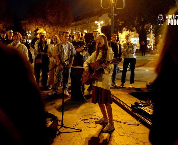 YOUNG PEOPLE CONGREGATE IN THE STREETS BEFORE CURFEW, SINGING AND DANCING TO RELEASE TENSION AND COLLECT MONEY FOR THE WAR EFFORT FOLLOWING THE ALL CLEAR FROM AN AIR SIREN. OCTOBER 2023.