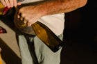 A close-up of an unidentified man using a corkscrew to open a bottle of organic wine inside a small, family-owned winery.